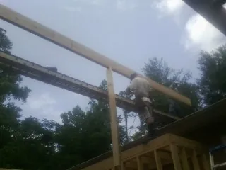 Carpenter setting a ridge beam over a new addition frame — Ice Dam Removal by Roofing Brothers in Hartly