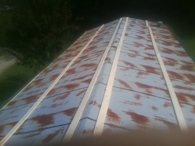 Rusted metal roof panels with new wood purlins before replacement — Storm Damage Roof Repair in Hartly by Roofing Brothers