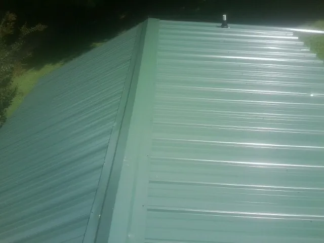 New green metal panels meeting at the ridge of a roof — Flat Roof Repair work by our crew in Hartly