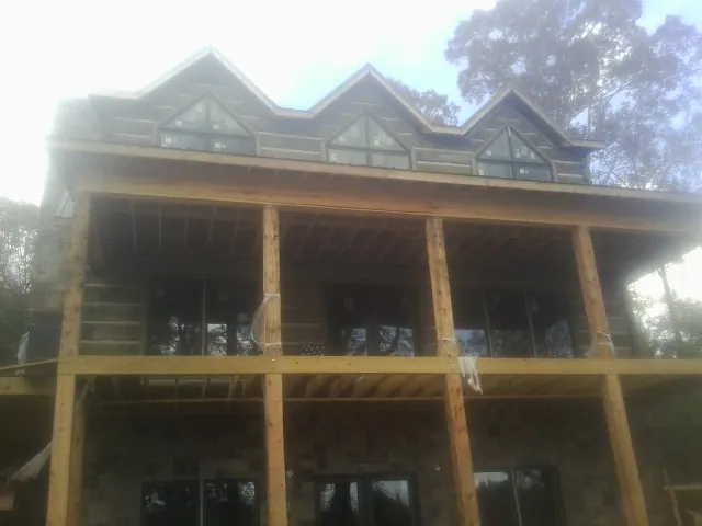 Dormers and porch framing on a large log home under construction — Roof Coating work by our crew in Hartly