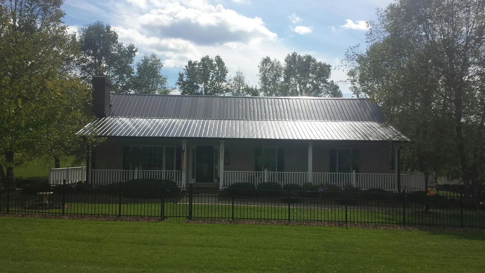 Gray metal roof on a brick ranch with a full width front porch — Gutter Guard Installation work by our crew in Hartly