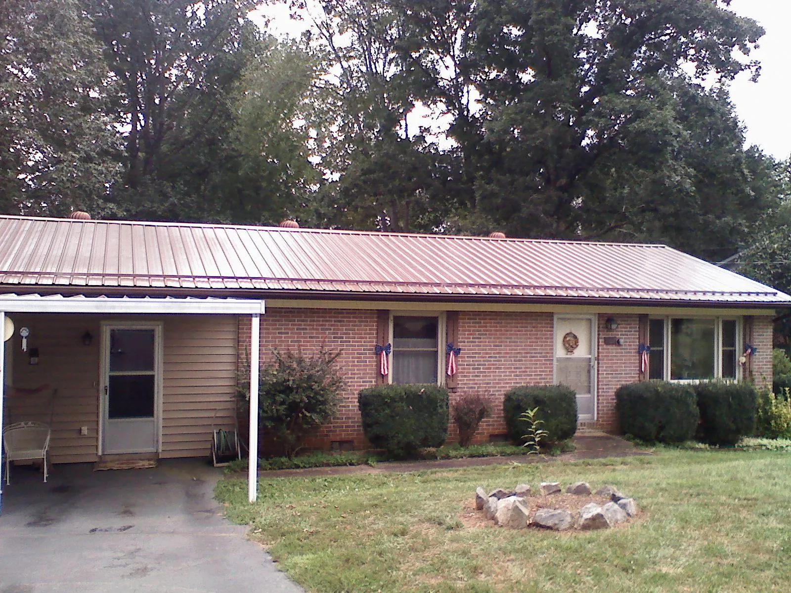 Bronze metal roof and carport on a brick ranch home — Roof Repair work by our crew in Hartly