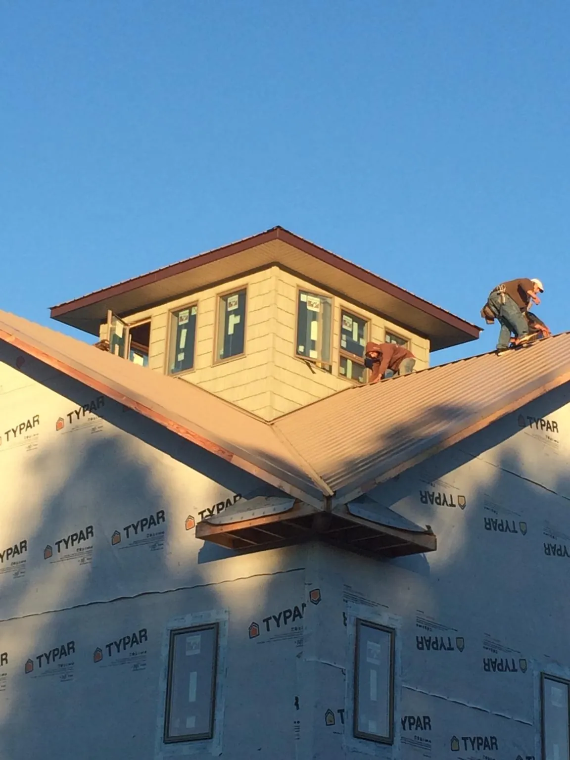 Roofers working around a rooftop cupola on a new metal roof at sunset — Roof Waterproofing in Hartly by Roofing Brothers